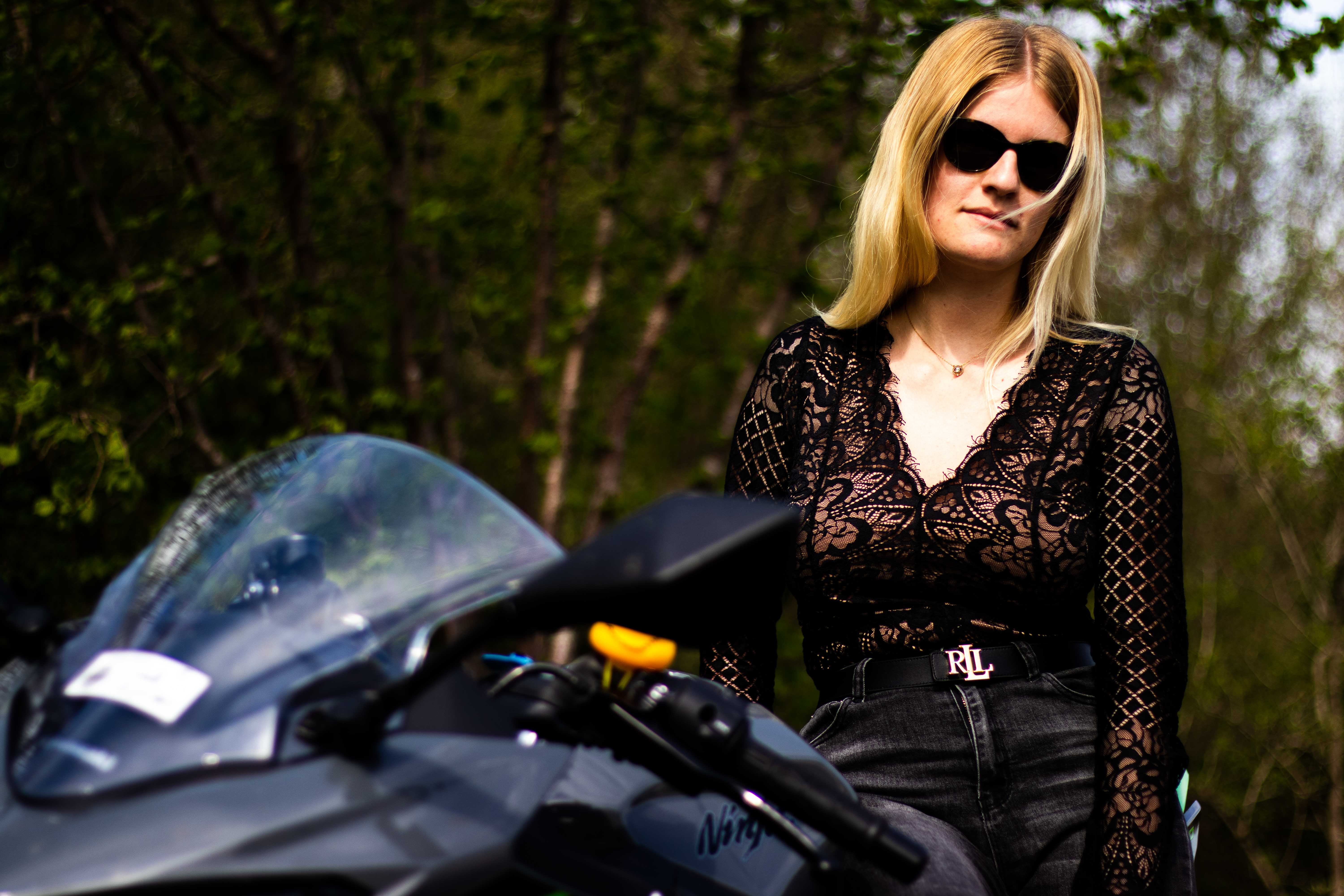 Photo d'une femmme assise sur une moto avec le regard vers l'appareil photo en vue contre-plongé